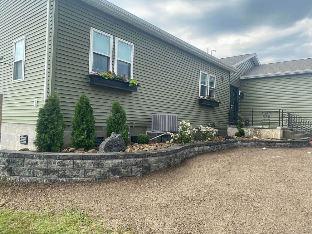 Modern home exterior with green siding, flower boxes, and landscaped stone garden.
