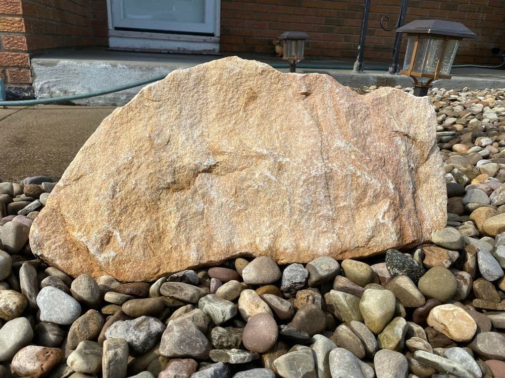 Natural stone rock on pebbled landscape, showcasing earthy tones and texture.