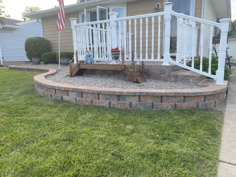 Front porch with white railing, stone steps, and landscaped yard, featuring a nearby flag.