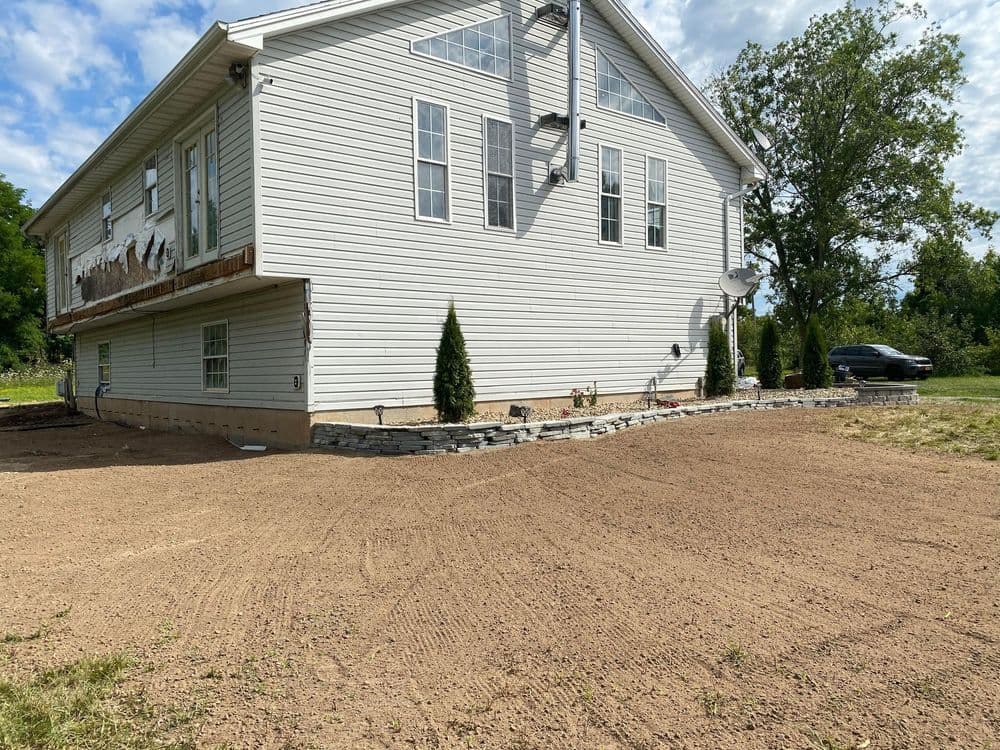 Newly landscaped home exterior featuring stone edging and gravel area for garden or patio.