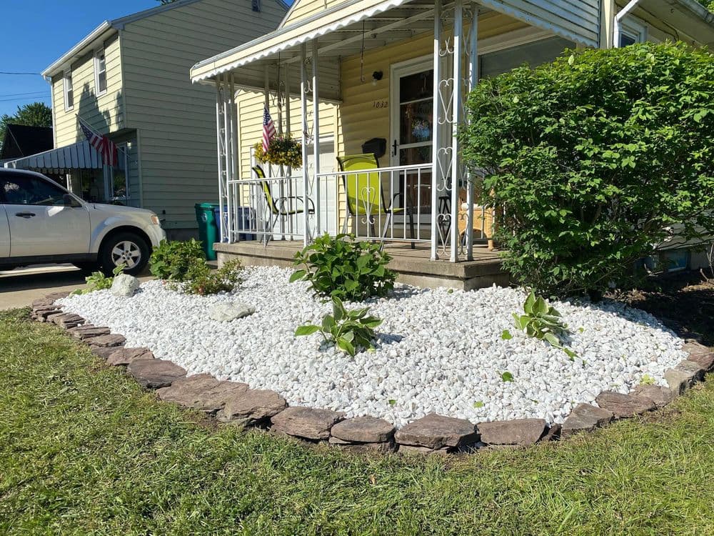 Residential front yard with white gravel landscaping, decorative stones, and green plants.
