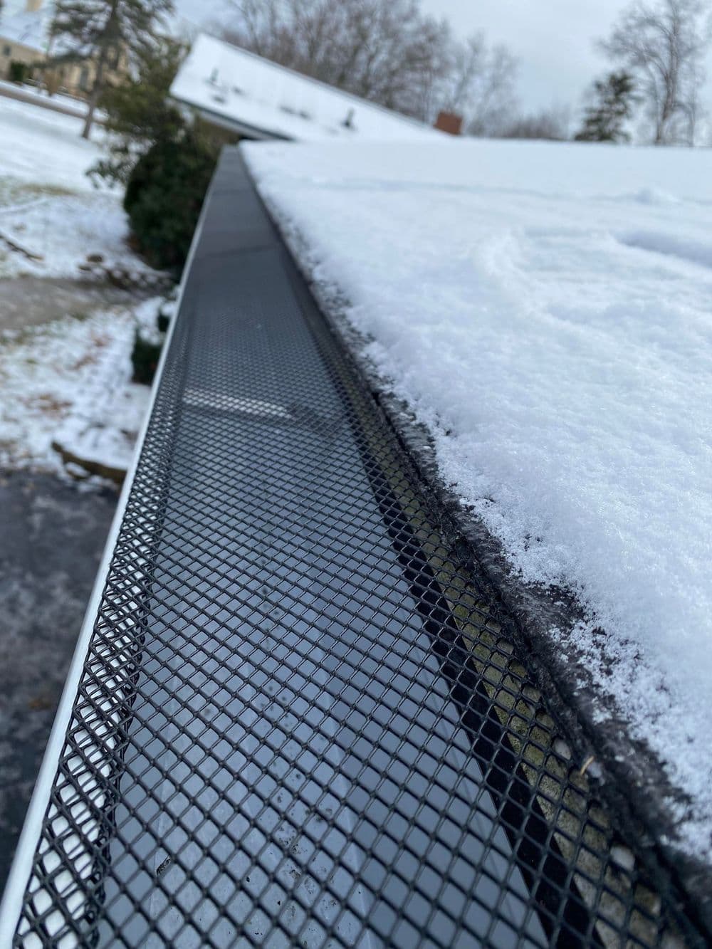 Snow-covered roof with a black gutter guard, enhancing drainage efficiency.