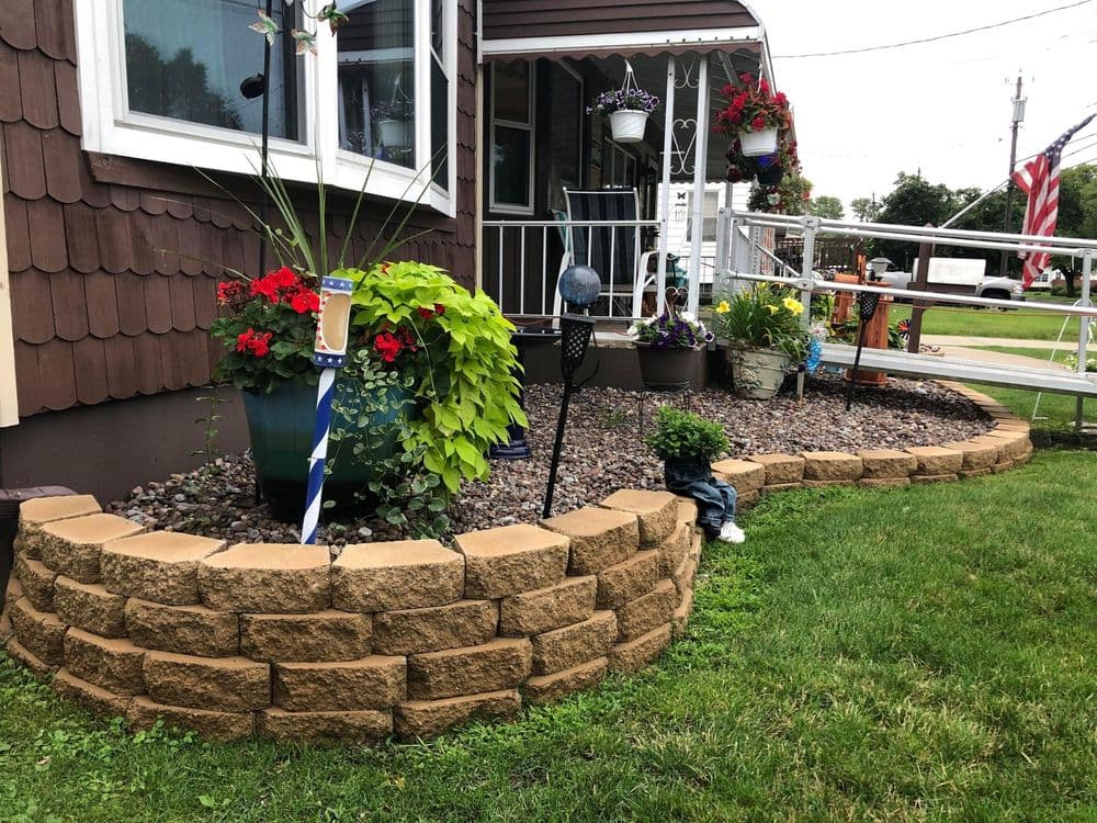 Flowering garden beds with colorful plants, decorative stones, and a charming porch.
