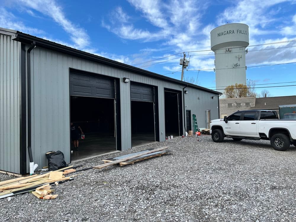 Niagara Falls industrial building with open garage doors and parked white pickup truck.