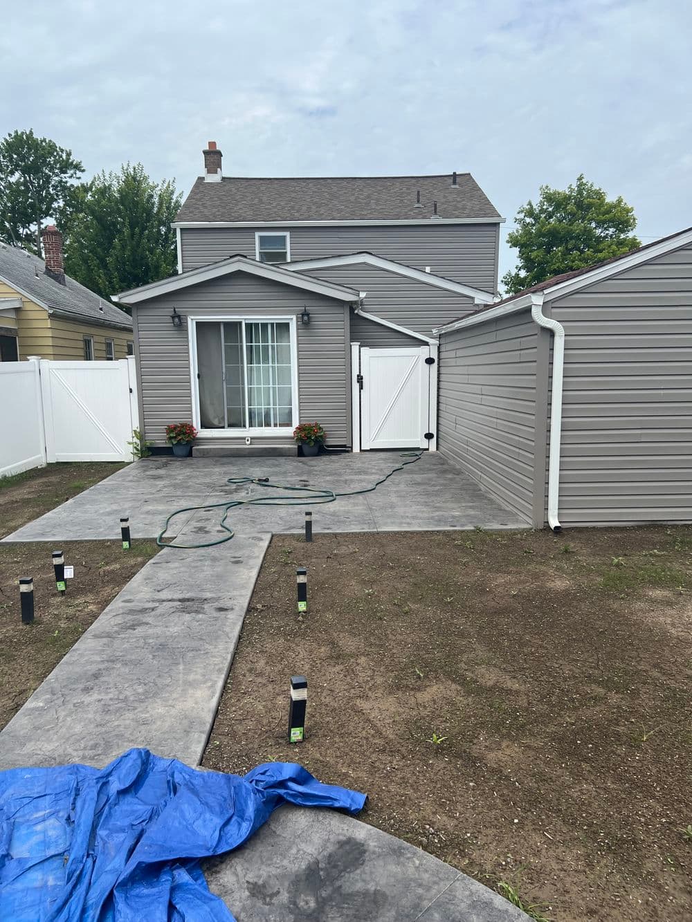 Home exterior with gray siding, patio area, and well-maintained landscaping.