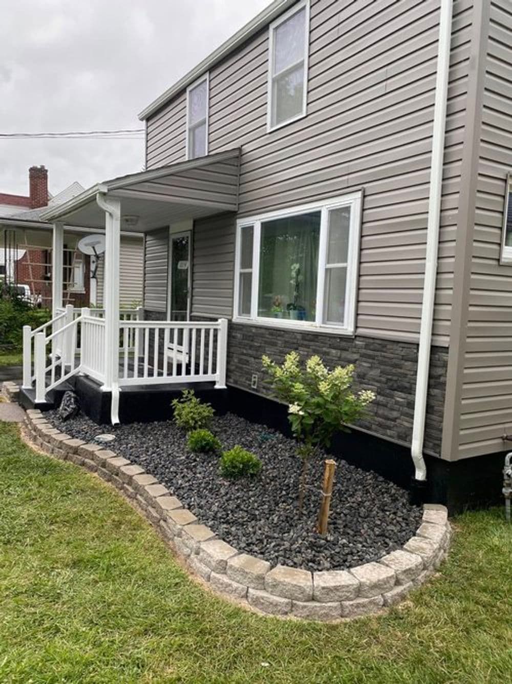 Modern home exterior with stone accents, landscaped garden, and welcoming front steps.