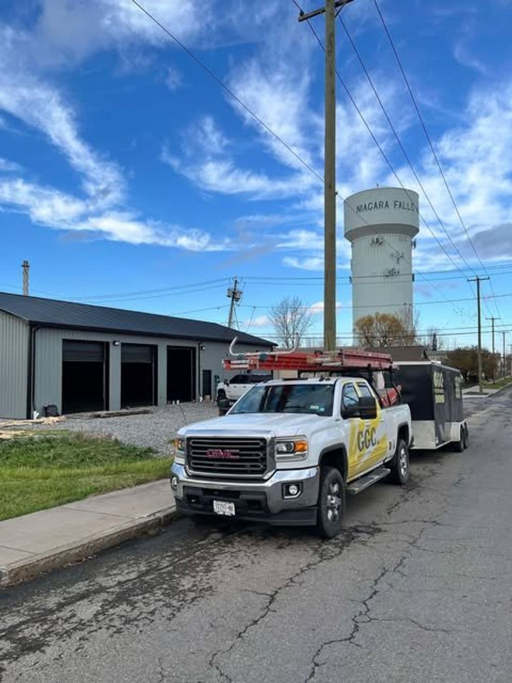 GMC truck with trailer parked near a building and water tower in Niagara Falls.